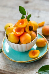 Ripe juicy apricots in a white bowl on a wooden background
