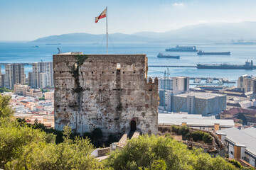 The Moorish Castle's Tower of Homage with a flag in Gibraltar and Africa in the horizon mountains - obrazy, fototapety, plakaty