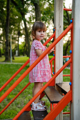 Obraz premium Cute baby girl Playing At Playground In Summer Sunny Day. Little girl licking chupa chups
