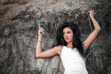 Brunette near the sandy slope covered with tree roots