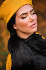 Makeup of a beautiful brunette in a yellow beret in autumn. portrait
of a beautiful brunette with makeup in a yellow beret and yellow jacket in autumn in the park.