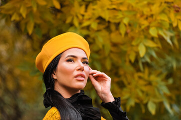 Makeup of a beautiful brunette in a yellow beret in autumn. portrait
of a beautiful brunette with makeup in a yellow beret and yellow jacket in autumn in the park.
