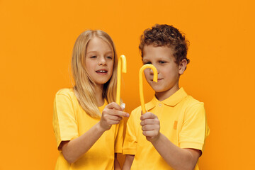 funny children stand with yellow caramel lollipops on a yellow background and smile joyfully