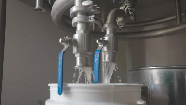 Dirty Liquid Runs From Open Pipes from beneath a Brewery's Mash Tun