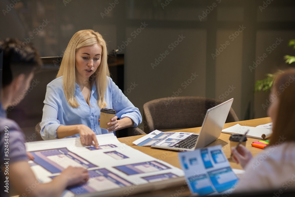 Wall mural group of three young marketing professionals analyzing and discussing printed website and applicatio
