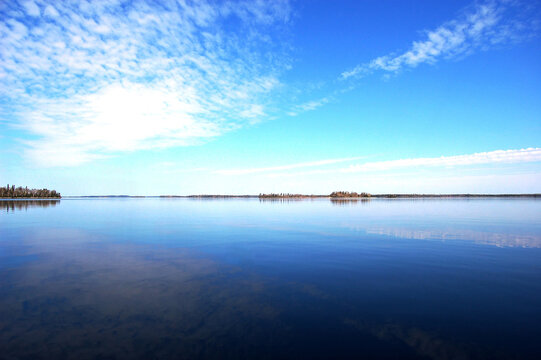 Breathtaking view of the natural reflections cast upon the calm glossy waters of Lac Seul, Ontario, Canada.