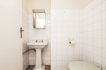 Simple vintage bathroom with white fixtures, small chrome cabinet with mirror and white square tiles