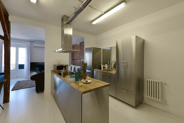 Open kitchen with stainless steel furniture, matching appliances with wooden countertops and access to a living room