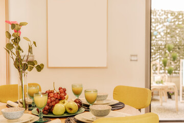 Dining room with round wooden table and yellow upholstered chairs, lots of fresh fruit and freshly squeezed orange juice