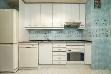 Front view of a kitchen with white wood cabinets, built-in appliances, pink granite countertops,...