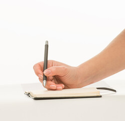 female hand writes in a notebook on a white background isolated