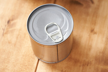 Iron tin can with tab opener on the wooden table.