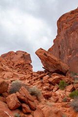 Hiking outdoors and encountering a steep scramble over rocks and red sandstone boulders in the high desert of the American southwest, the gray cloudy skies provide some relief from the sun