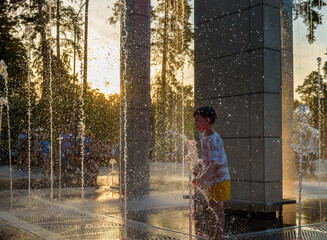 Boy having fun in water fountains. Child playing with a city fou