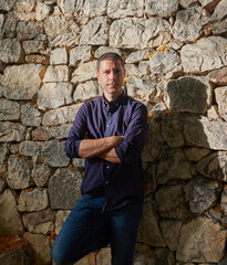 young man in blue shirt posing behind a wall