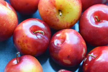 Juicy red ripe plums on a blue plate. Vegan concept. Healthy organic food.