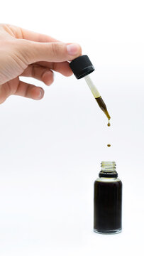 Mano que sostiene un gotero de aceite de canabis puro