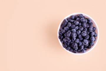 Top view of fresh juicy ripe blueberries in bowl isolated on beige. Flat lay copy space. Healthy berry, organic food, antioxidant, vitamin, blue food. Blueberry pattern