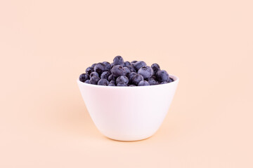 Beautiful fresh blueberries in a white bowl on a beige background.Vegan and vegetarian concept. Summer healthy food.