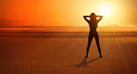 happy woman with hands in her hair enjoying sunset on the beach. Have a positive mindset.