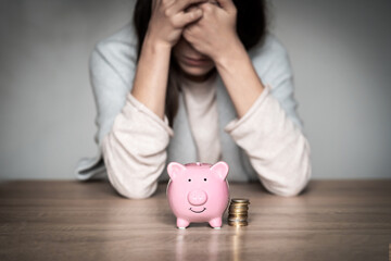 Sad girl with a piggy bank at home.