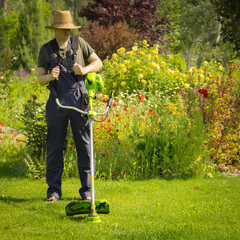 A young man with a lawnmower cares for the grass in the backyard.