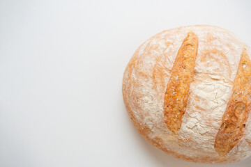 A close-up of a whole fresh crispy delicious round-shaped wheat bread on a white background. Insulated items, baking, top vew, flat lay, copy space