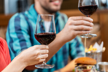 leisure, people and celebration concept - close up of happy friends drinking red wine and toasting at restaurant or pub