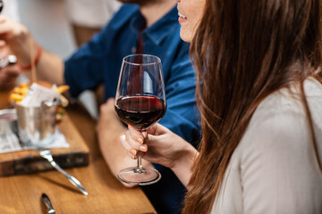 leisure, drinks and people concept - close up of happy woman with glass drinking red wine at restaurant