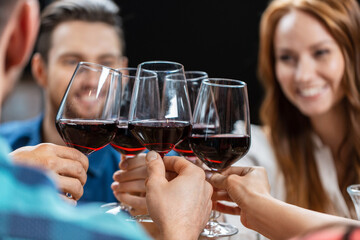 leisure, people and celebration concept - close up of happy friends drinking red wine and toasting at restaurant or pub