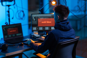 cybercrime, hacking and technology concept - male hacker in dark room writing code or using...