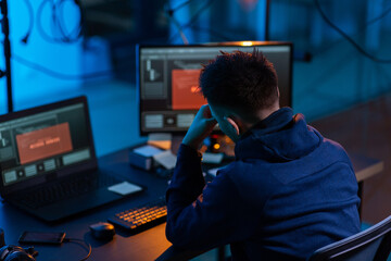 cybercrime, hacking and technology concept - male hacker in dark room writing to notebook and using...
