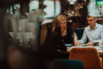 Happy businesspeople smiling cheerfully during a meeting in a coffee shop. Group of successful business professionals working as a team in a multicultural workplace.