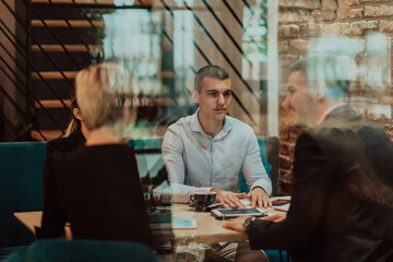 Happy businesspeople smiling cheerfully during a meeting in a coffee shop. Group of successful business professionals working as a team in a multicultural workplace.