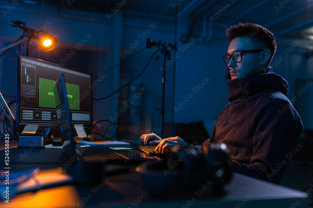 Poster cybercrime, hacking and technology concept - male hacker in dark room writing code or using computer