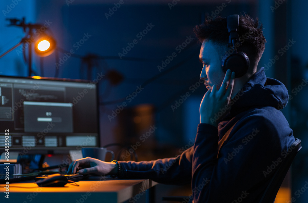 Poster cybercrime, hacking and technology concept - male hacker in dark room writing code or using computer