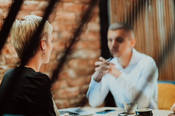 Happy businesspeople smiling cheerfully during a meeting in a coffee shop. Group of successful business professionals working as a team in a multicultural workplace.