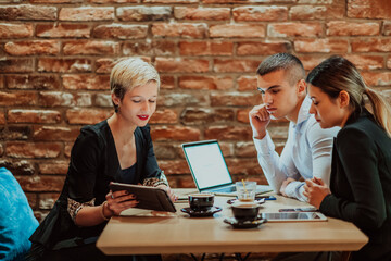 Happy businesspeople smiling cheerfully during a meeting in a coffee shop. Group of successful business professionals working as a team in a multicultural workplace.