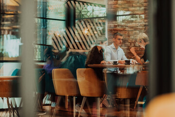 Happy businesspeople smiling cheerfully during a meeting in a coffee shop. Group of successful business professionals working as a team in a multicultural workplace.