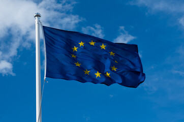 Flag of EU on blue sky background. European Union flag waving in wind. 