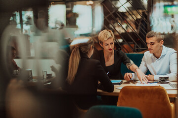 Happy businesspeople smiling cheerfully during a meeting in a coffee shop. Group of successful business professionals working as a team in a multicultural workplace.