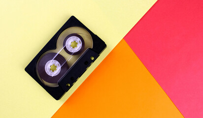 Audio cassette with tape on tricolor (yellow, red, orange) background