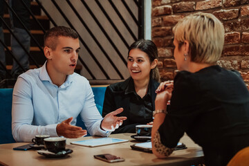 Happy businesspeople smiling cheerfully during a meeting in a coffee shop. Group of successful business professionals working as a team in a multicultural workplace.