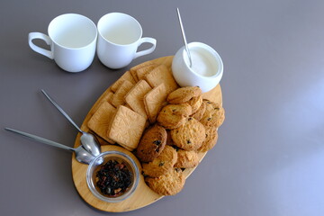 A tasty snack two cups of black tea and a plate of oatmeal cookies a wooden board on the gray background, leaf tea.