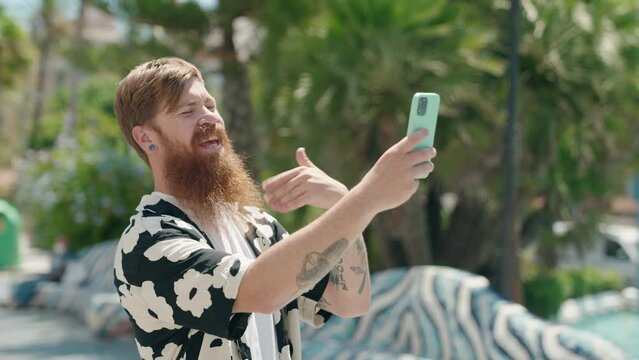 Young redhead man smiling confident having video call at park