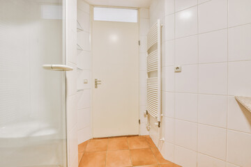 Shower faucets attached to tiled wall near glass partition and ornamental curtail in washroom at...