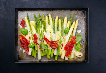 Traditional oven baked white and green asparagus with cheese, sauce hollandaise and bacon served as...