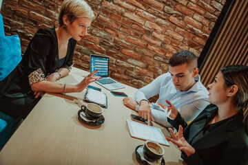 Happy businesspeople smiling cheerfully during a meeting in a coffee shop. Group of successful business professionals working as a team in a multicultural workplace.