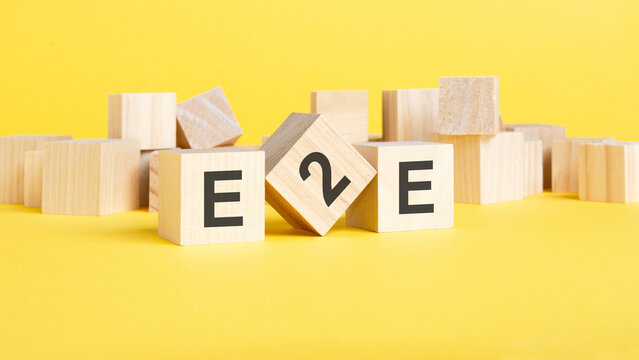 wooden blocks with word e2e on yellow background. end to end concept