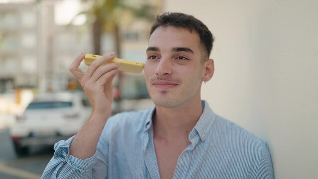 Young hispanic man smiling confident listening audio message by the smartphone at street